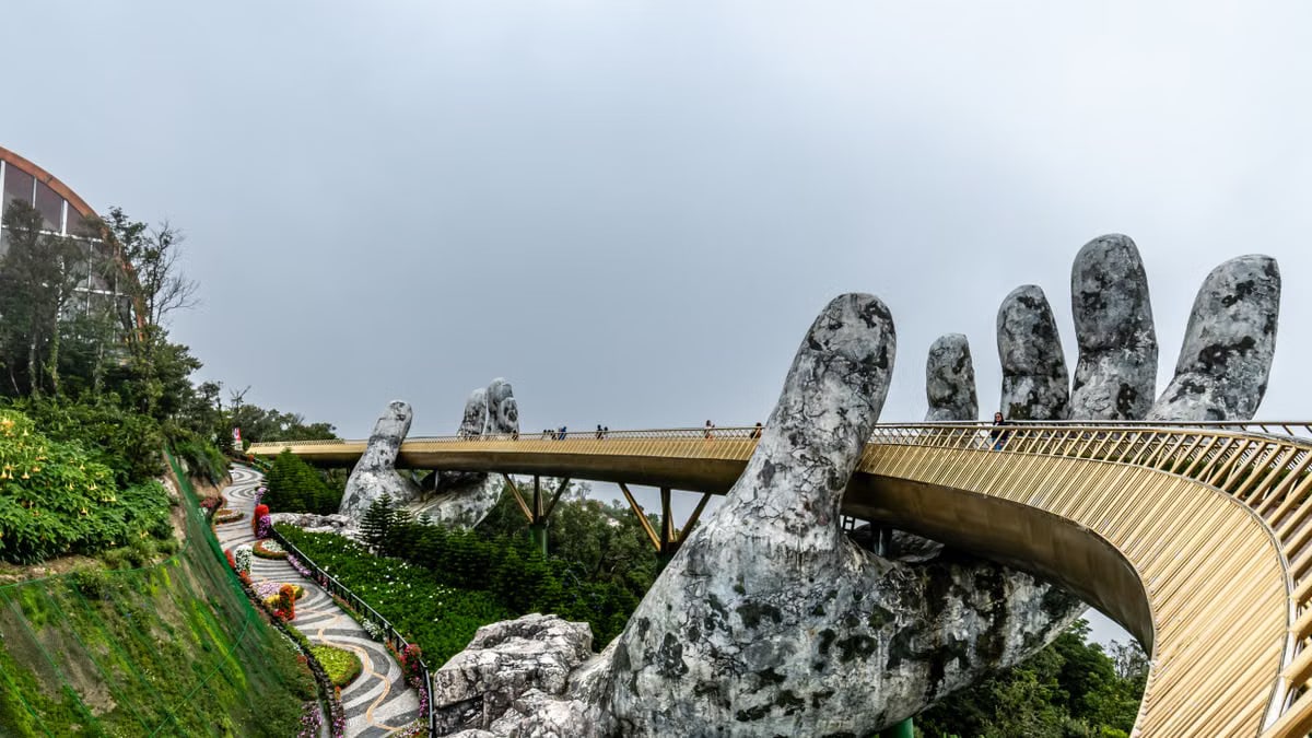 Explore the iconic Golden Bridge in Da Nang, Vietnam, held by giant stone hands amidst lush greenery.